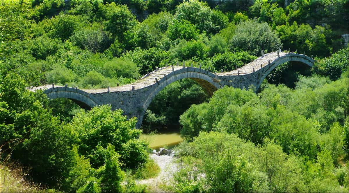 Το τρίτοξο πέτρινο γεφύρι της Πλακίδας μέσα στο πράσινο